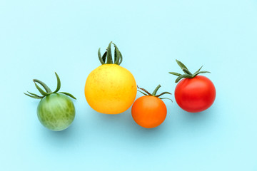 Colorful organic cherry tomatoes on a blue background, creative flat lay healthy food concept, top view