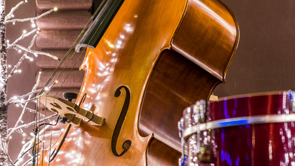 Close up of a cello, christmas lights and glitters are in the background.