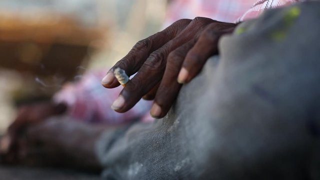 A close up  side shot of a mans hand holding a burning ciggerate 