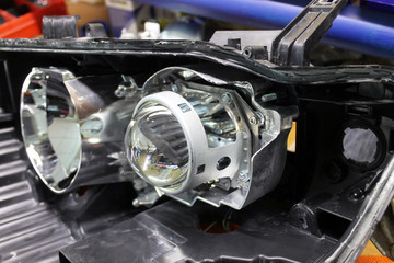 Fototapeta premium Repairing, installation and tuning headlight of modern automobile and car projector lens. Vehicle head xenon lamp in details. Concept of auto detailing, light and LED technology