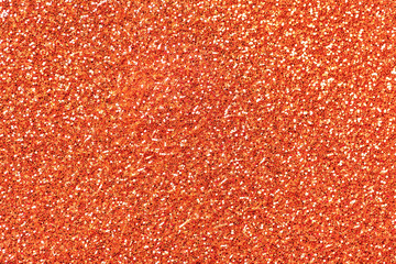 Light orange sparkling background from small sequins, closeup. Brilliant backdrop.