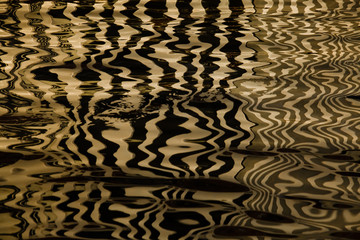 Waves on the water forming stripes similar to the texture of velvet, the alternation of gold and...