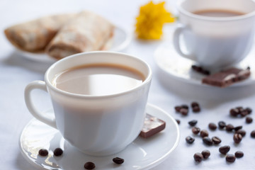 Two cup of coffee with milk, pancakes with jam and milk chocolate. Morning breakfast for two.