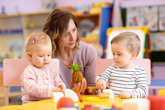 Preschool teacher with babies playing with colorful toys at kindergarten