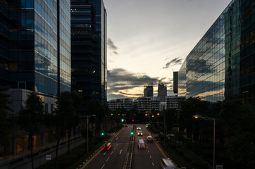 Fototapeta na wymiar Cars rushing through streets of modern city on sunset sunrise