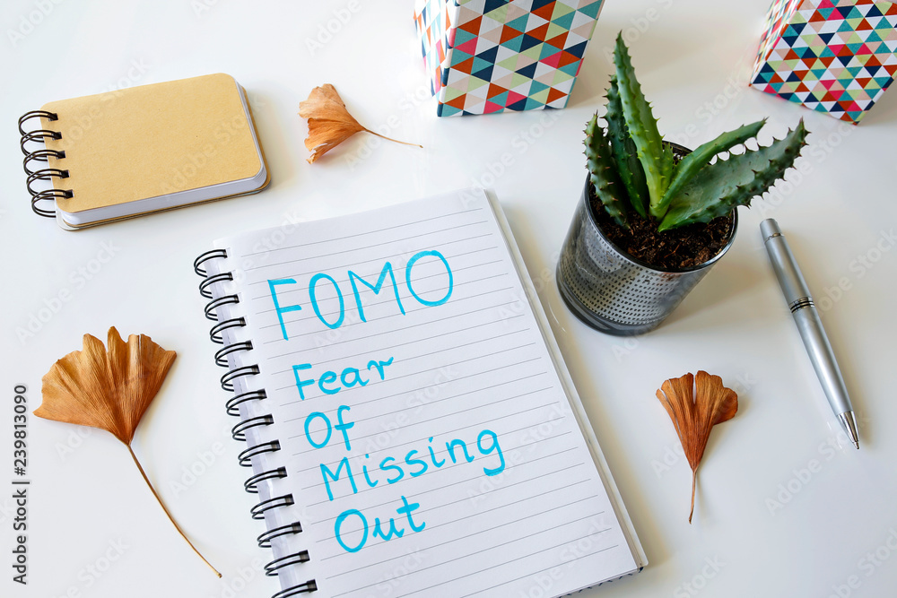 Poster fomo fear of missing out written in a notebook on white table