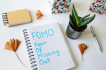 FOMO fear of missing out written in a notebook on white table