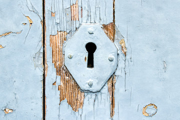 A metal hole for a key on the blue wooden planks. Old wooden planks.