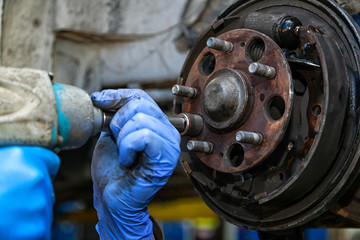 Close-up replacement of the old front brake disc, brake caliper and hub nut on a car raised on a...