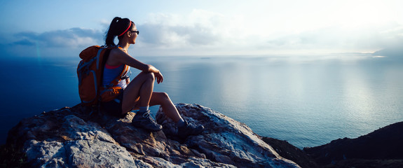young woman hiker at sunrise seaside mountain peak