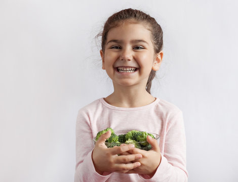 Happy smiling child girl eating vegetables. Healthy food. Fresh broccoli.