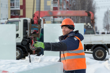 Slinger in an orange helmet on unloading ice blocks