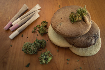 Cannabis edible: homemade cookies made with marijuana. Cookies, some joints and marijuana buds on wooden background. Top view.