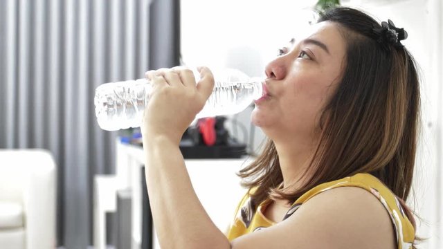 Asian woman drinks mineral water from bottle. Beautiful girl with long hair 
 drinks clean water. Slow motion 4K