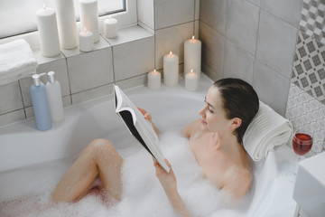 Young woman relaxes in a hot bath full of foam.