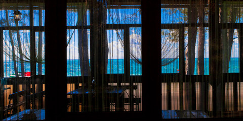 Through the window you can see the cafe's atmosphere and the blue and turquoise sea and sky.