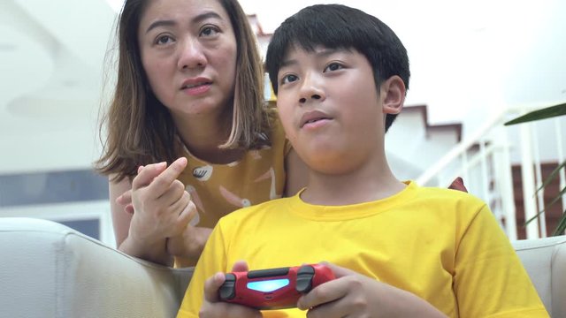 Asian mother and son playing video game at home together.4K Slow motion