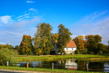Fototapeta na wymiar Country estate near the lake and forest, sunny autumn day. Leaf fall landscape.