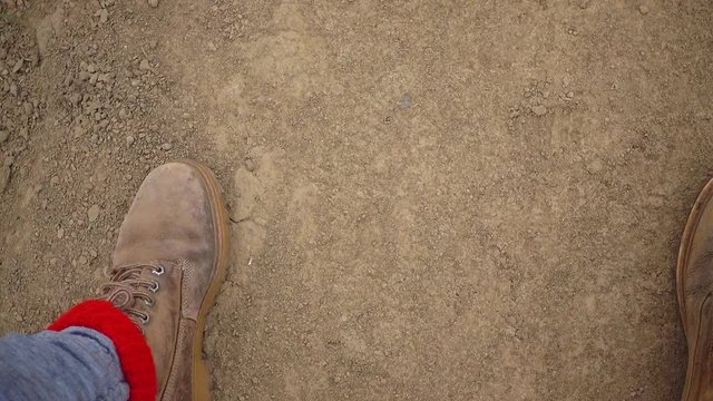 Top view of red boots walking along the ground.

