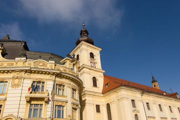 Fototapeta na wymiar The Town Hall of Sibiu, Transylvania, Romania, A flock of pigeons circling over the roof