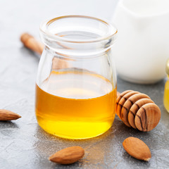 Honey background. Sweet honey in glass jar with almonds. On gray background.