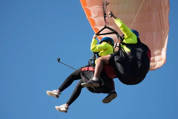 Zelfklevend Fotobehang Luchtsport Paraglider tandem vliegen tegen de blauwe lucht, tandem paragliden onder begeleiding van een piloot