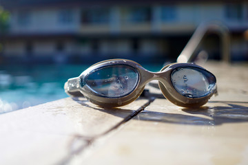 Swimming goggle at pool side on morning sunlight