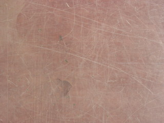 Glass texture with transparent scratched worn surface and pale red background 