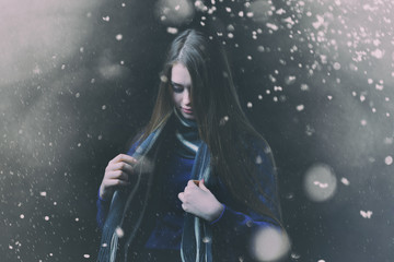 Fototapeta na wymiar Beautiful, young girl with blond hair in a blue sweater on a snowfall in winter