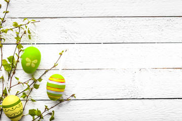 Easter egg on white wooden background. Spring decoration with painted eggs hanging on branch.