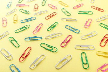 Background made from colored paper clips on the light yellow base