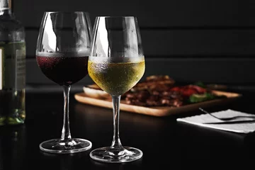Photo sur Plexiglas Vin White and red wine pouring in glasses on wooden background