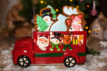 Holiday traditional food bakery. Decorative toy car with christmas Gingerbread cakes in cozy warm decoration with garland lights