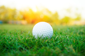 Blurred golf ball on green in beautiful golf course with sunset. Golf ball close up in golf coures at Thailand