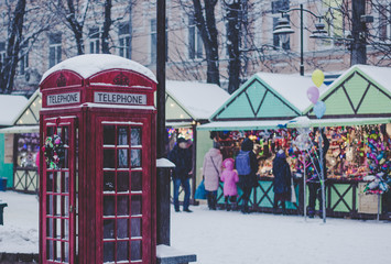 red classic phone booth in winter snowing season weather time and in Christmas fair city environment