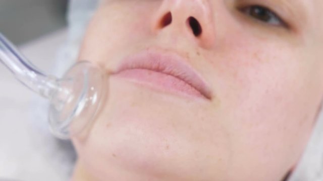 Beauty treatment facial electric darsonval therapy at cosmetology clinic.