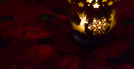 Christmas candle holder alight with a holdiay red glow, depicts scenes of winter and snow by the...