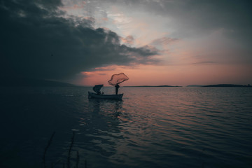 A fisherman tries to catch fish in sunset