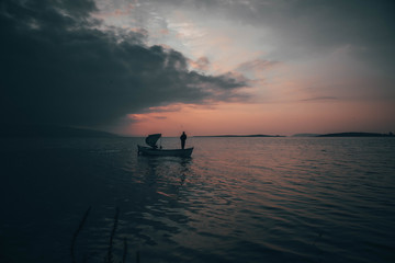 Naklejka na ściany i meble A fisherman tries to catch fish in sunset