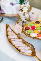 Candy bar table set. Cookies, eclairs, macaroons, fruits, cream and layered cakes. Pastel violet colours.