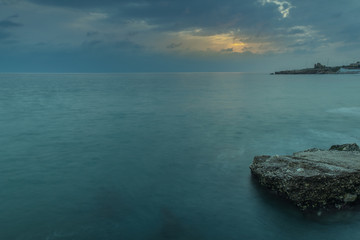 Nerja, Malaga, Andalusi, Spain - November 16, 2018: Long exposure on the coast with a rock in the foreground under a stormy sky