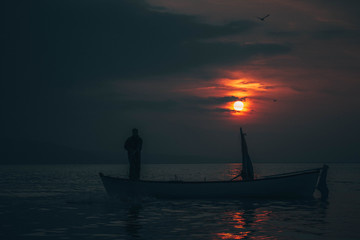 Sun goes down while fisherman throws his fishnet to collect fishes