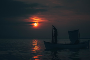Sun goes down while fisherman throws his fishnet to collect fishes