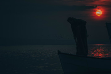 Sun goes down while fisherman throws his fishnet to collect fishes
