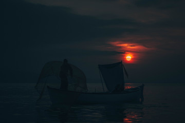 Sun goes down while fisherman throws his fishnet to collect fishes
