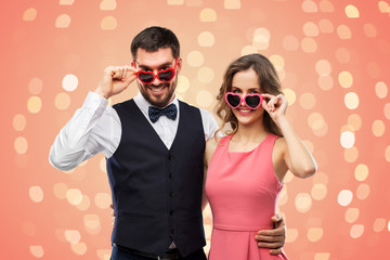 valentines day, love and people concept - happy couple in heart-shaped sunglasses over living coral...