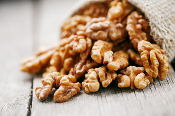 Walnuts in a burlap bag on a wooden gray background.