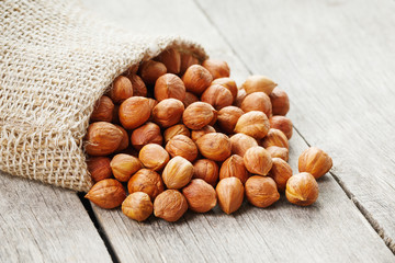 Chiselled hazelnuts in a bag of burlap on a gray wooden table. Organic Fresh Harvested