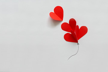 Valentines day card. Red paper heart shape balloons on thread. Paper cut style and minimalist...