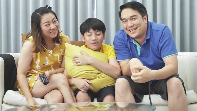Slow motion of asian family father mother and son on couch, Looking at camera  with smile face.